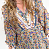 Woman wearing a patterned dress with long sleeves on a white background