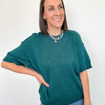 Woman wearing a green sweater and blue jeans against a white background