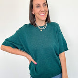 Woman wearing a green sweater and blue jeans against a white background