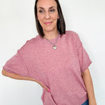 Woman wearing a pink sweater and blue jeans against a white background