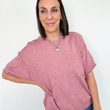 Woman wearing a pink sweater and blue jeans against a white background