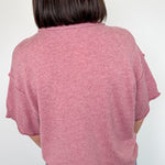 Person wearing a pink sweater and blue jeans against a white background