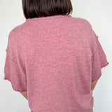 Person wearing a pink sweater and blue jeans against a white background