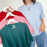 Woman holding a rack of sweaters in red, pink, and green.