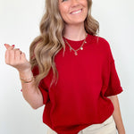 Woman wearing a red shirt and beige pants against a white background