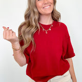Woman wearing a red shirt and beige pants against a white background