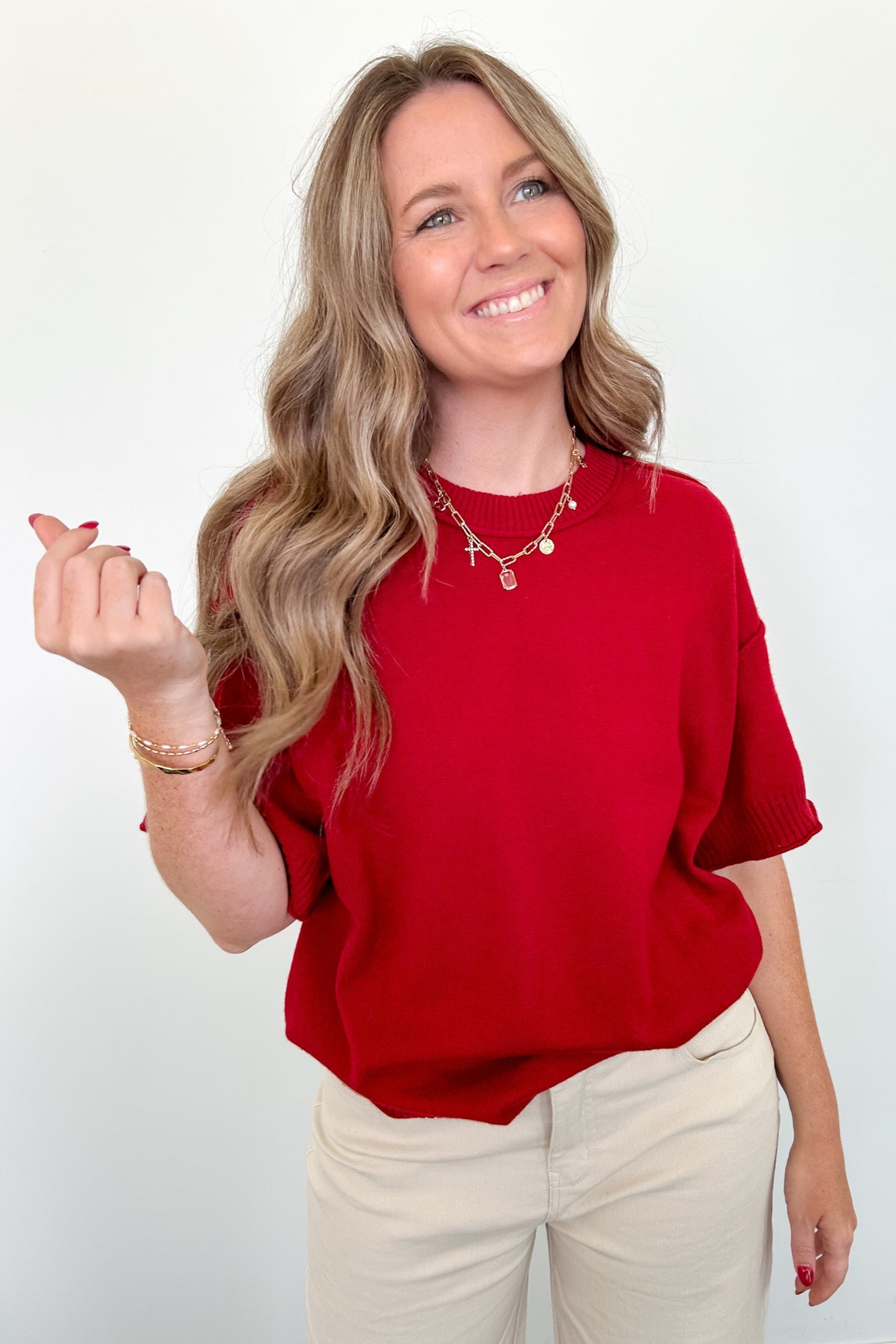 Woman wearing a red shirt and beige pants against a white background