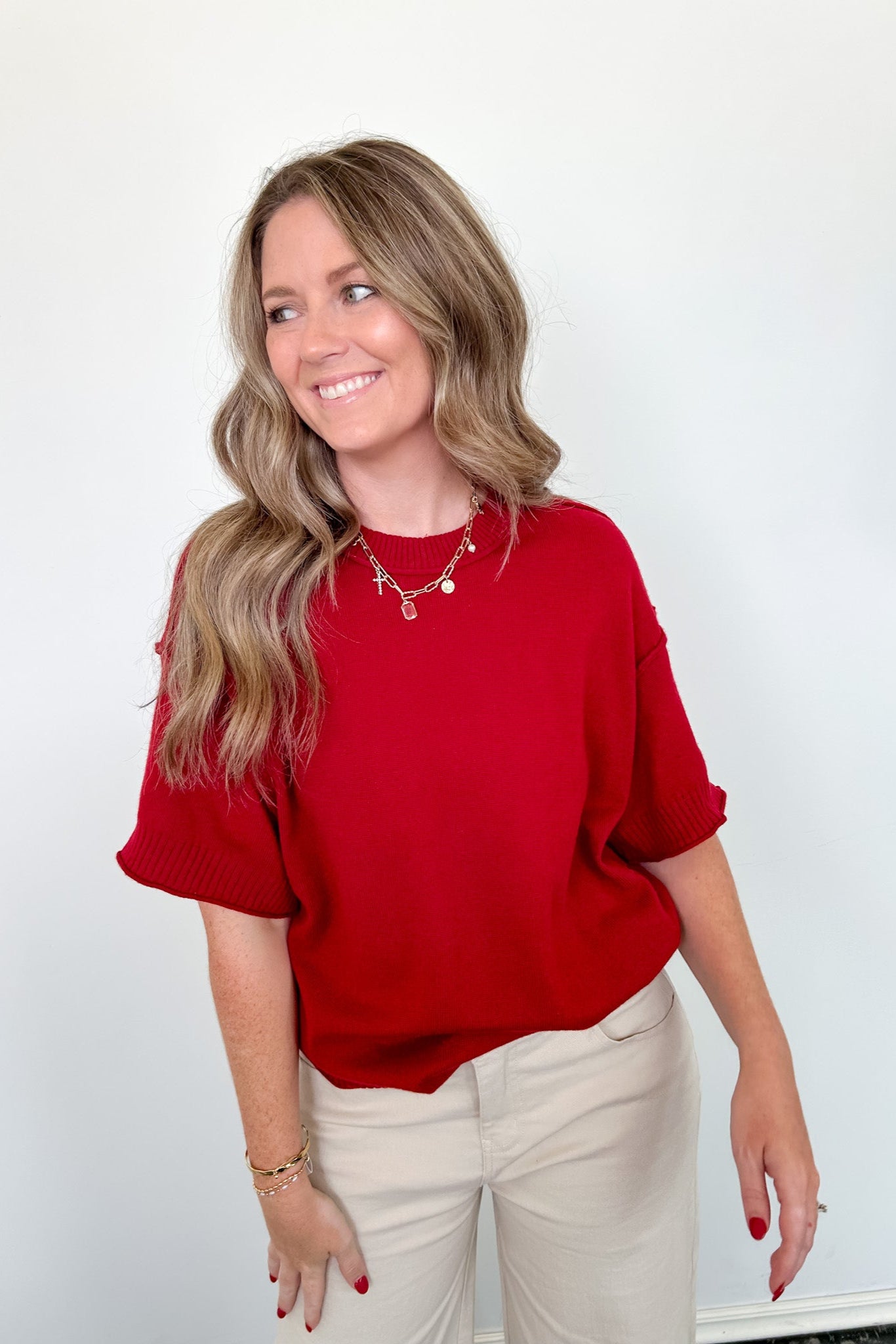 Woman wearing a red top and beige pants against a white background