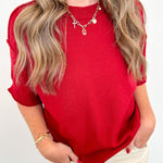 Person wearing a red top and beige pants against a white background