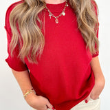 Person wearing a red top and beige pants against a white background