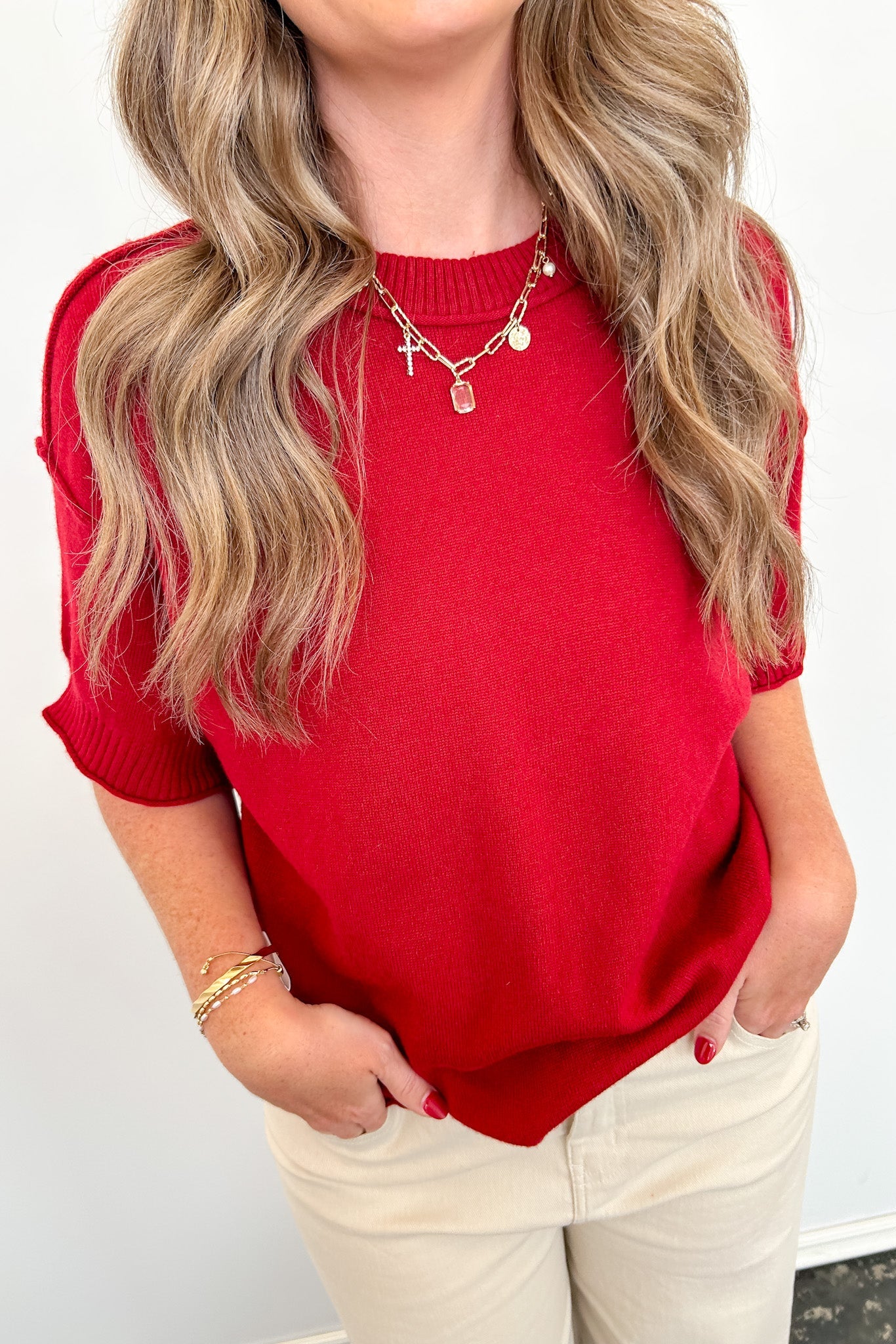 Person wearing a red top and beige pants against a white background