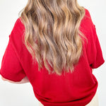 Person wearing a red sweater with a plain background