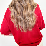 Person wearing a red sweater with a plain background