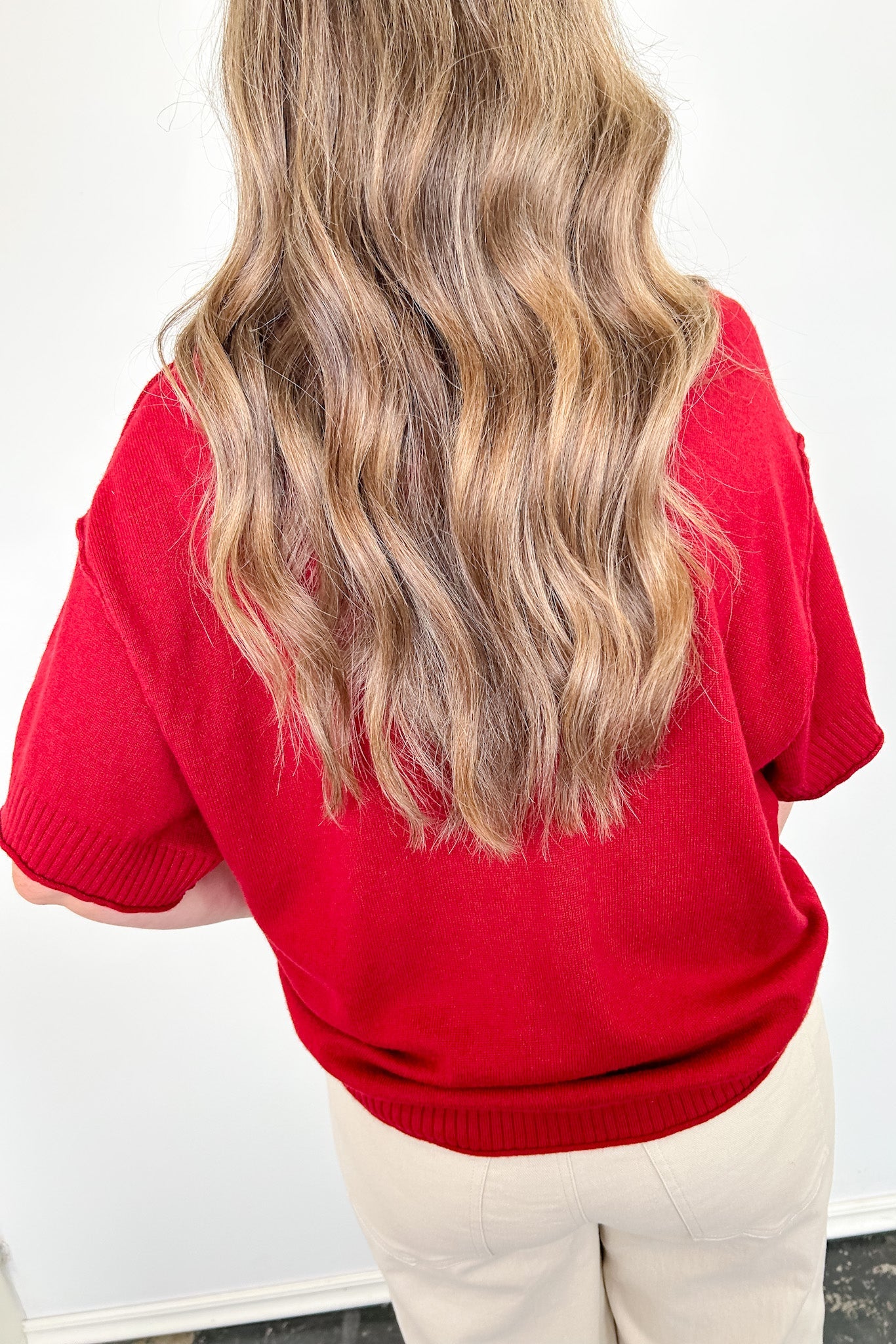 Person wearing a red sweater with a plain background