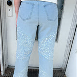 Person wearing light blue jeans with lace details standing in front of a door.