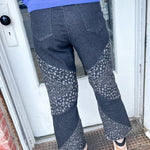 Person wearing blue sweater and patterned pants standing at a door.