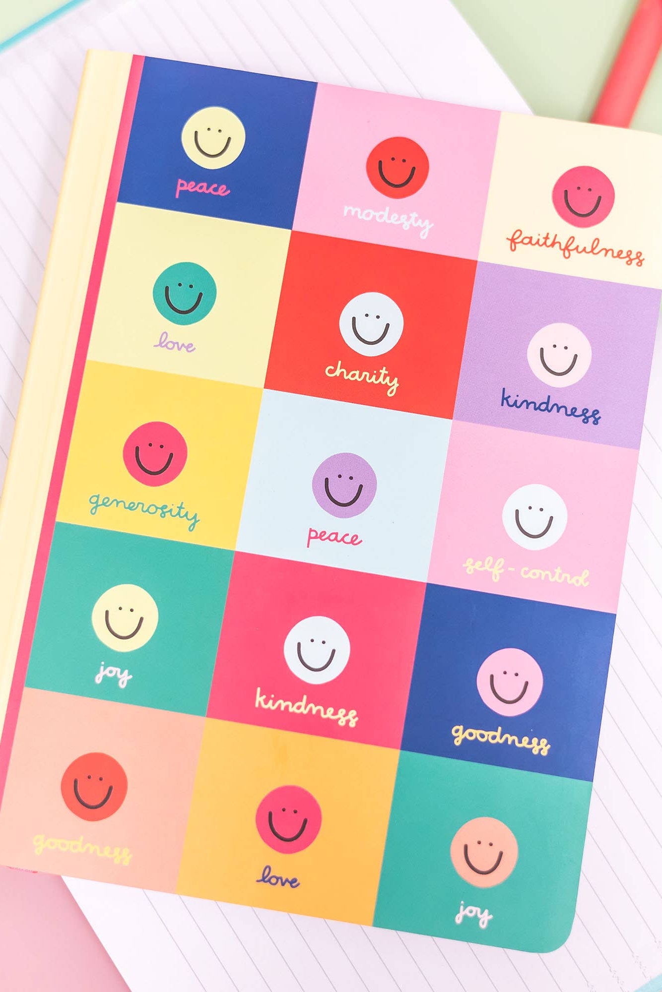 Notebook with colorful smiley face design on a light green background