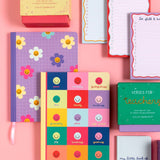 Collection of colorful journals and notebooks on a pink background
