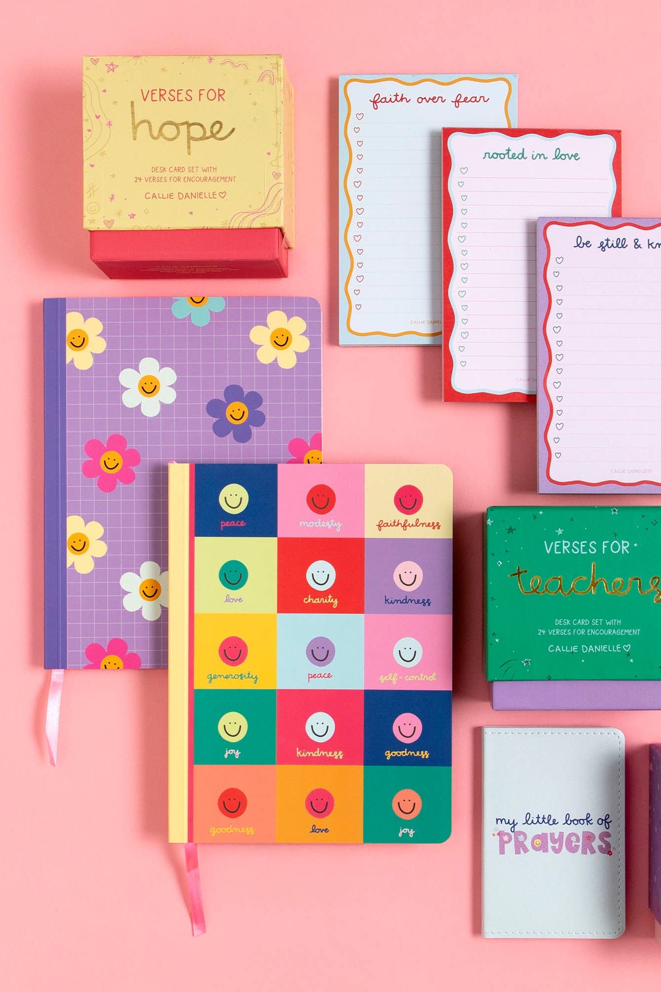 Collection of colorful journals and notebooks on a pink background