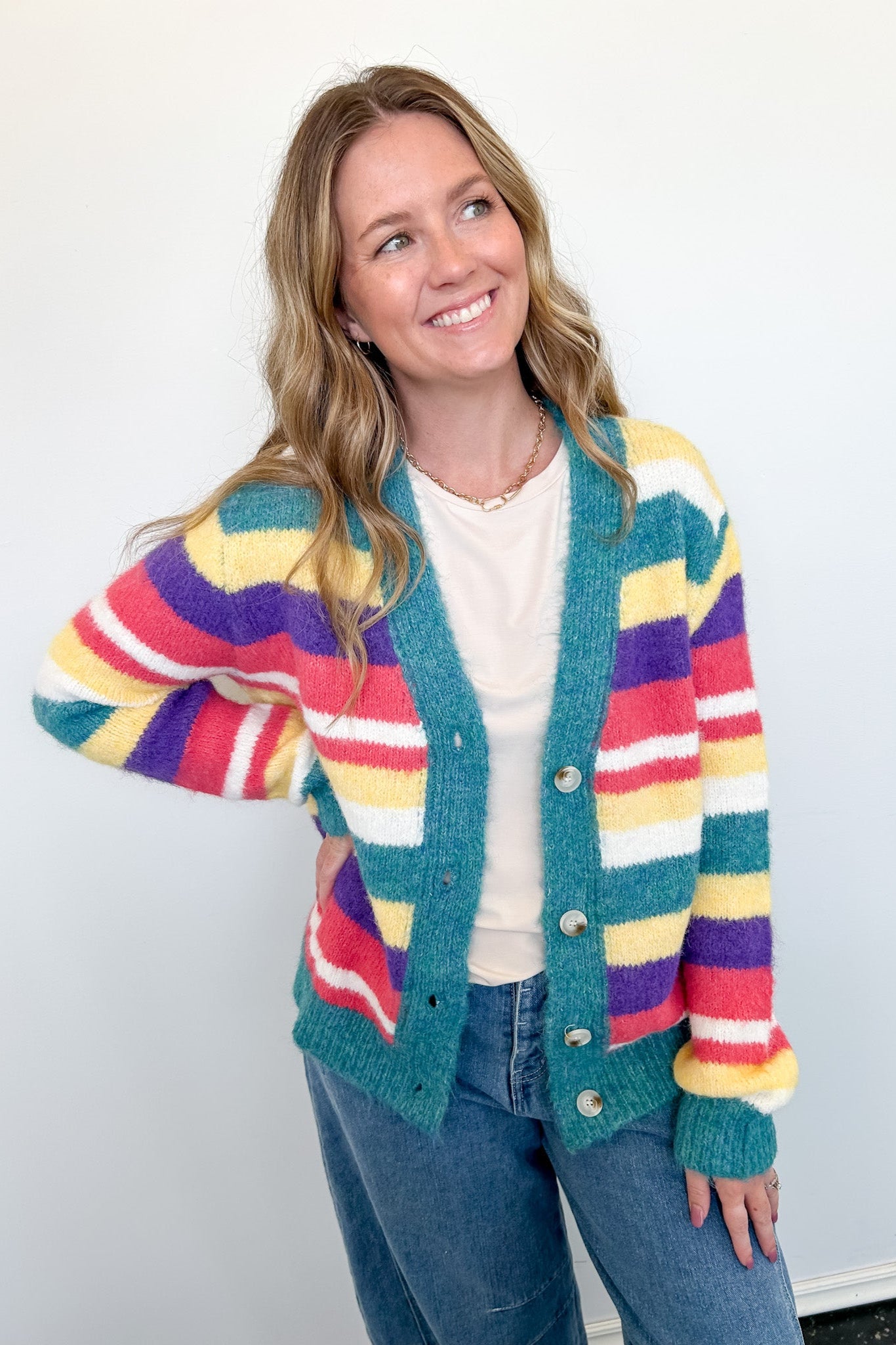Woman wearing a colorful striped cardigan against a white background