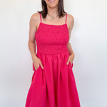 Woman wearing a bright pink dress against a white wall