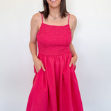 Woman wearing a bright pink dress against a white wall