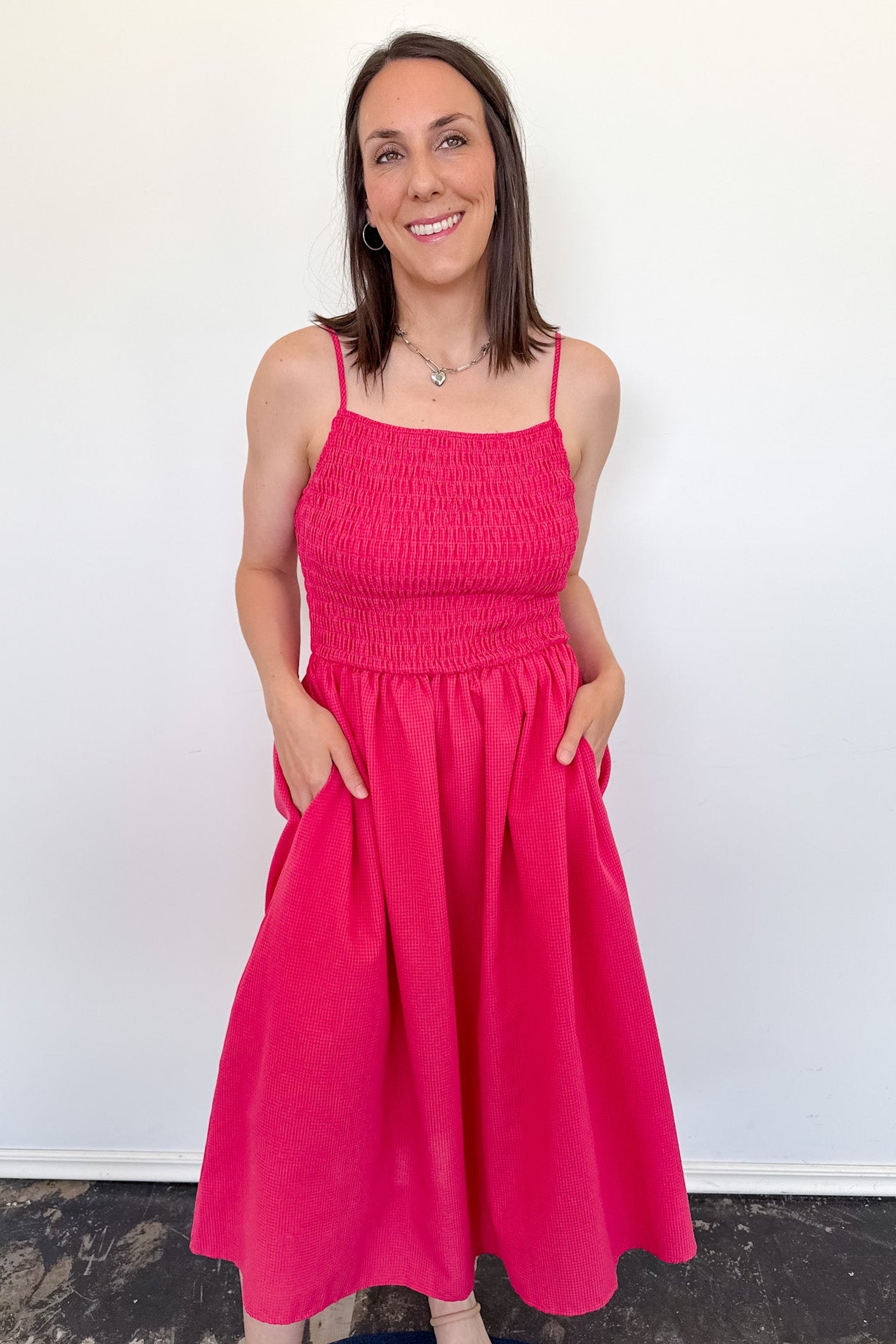 Woman wearing a bright pink dress against a white wall