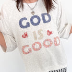 Person wearing a white t-shirt with 'GOD IS GOOD' text, standing indoors.