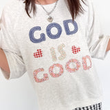 Person wearing a white t-shirt with 'GOD IS GOOD' text, standing indoors.