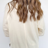 Person wearing a beige jacket and blue jeans against a white background