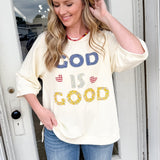 Woman wearing a 'God is Good' t-shirt standing in front of a door.