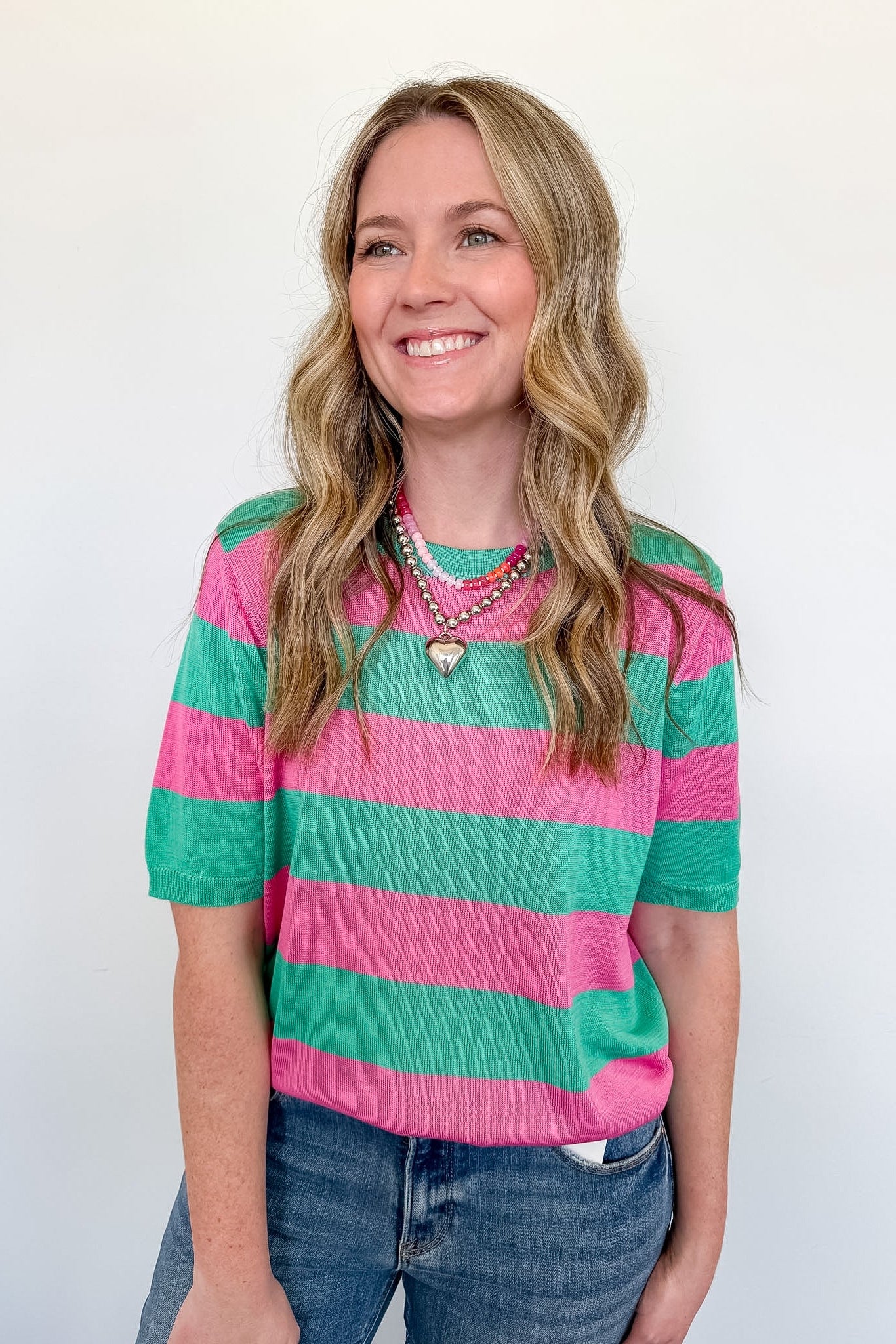 Woman wearing a pink and green striped sweater against a white background