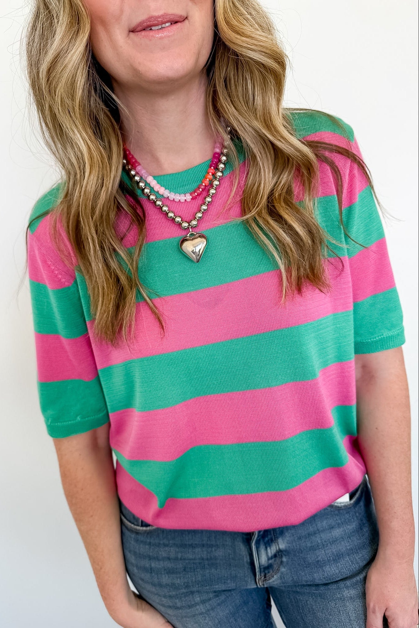 Woman wearing a pink and green striped shirt with a white background