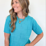 Woman wearing a turquoise sweater against a white background