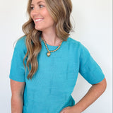 Woman wearing a turquoise sweater against a white background