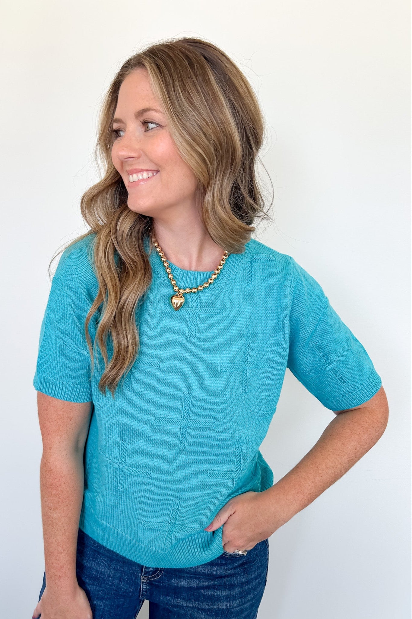 Woman wearing a turquoise sweater against a white background