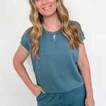 Woman wearing a teal outfit against a white background