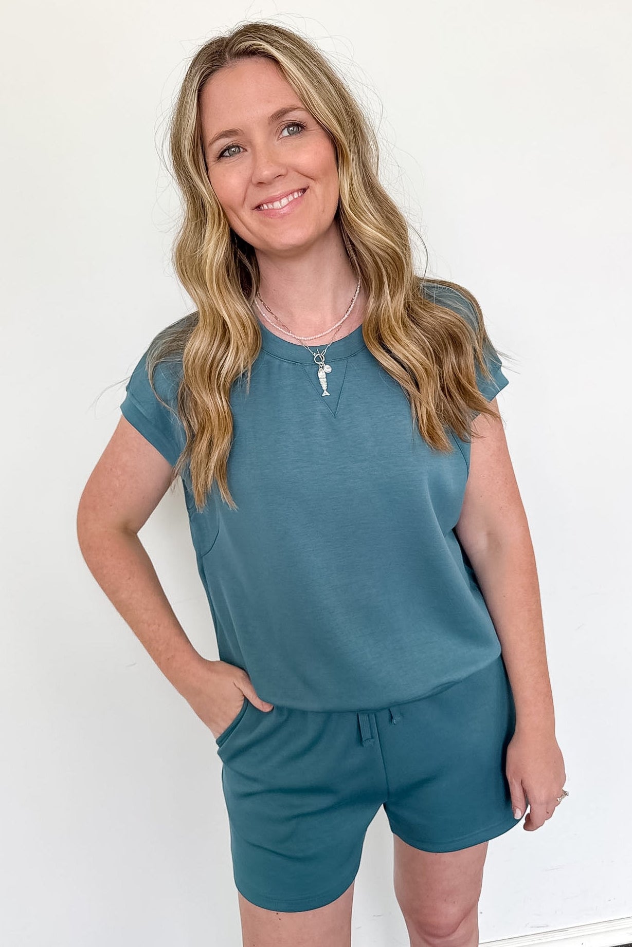 Woman wearing a teal outfit against a white background