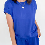 Person wearing a blue outfit with a white wall background