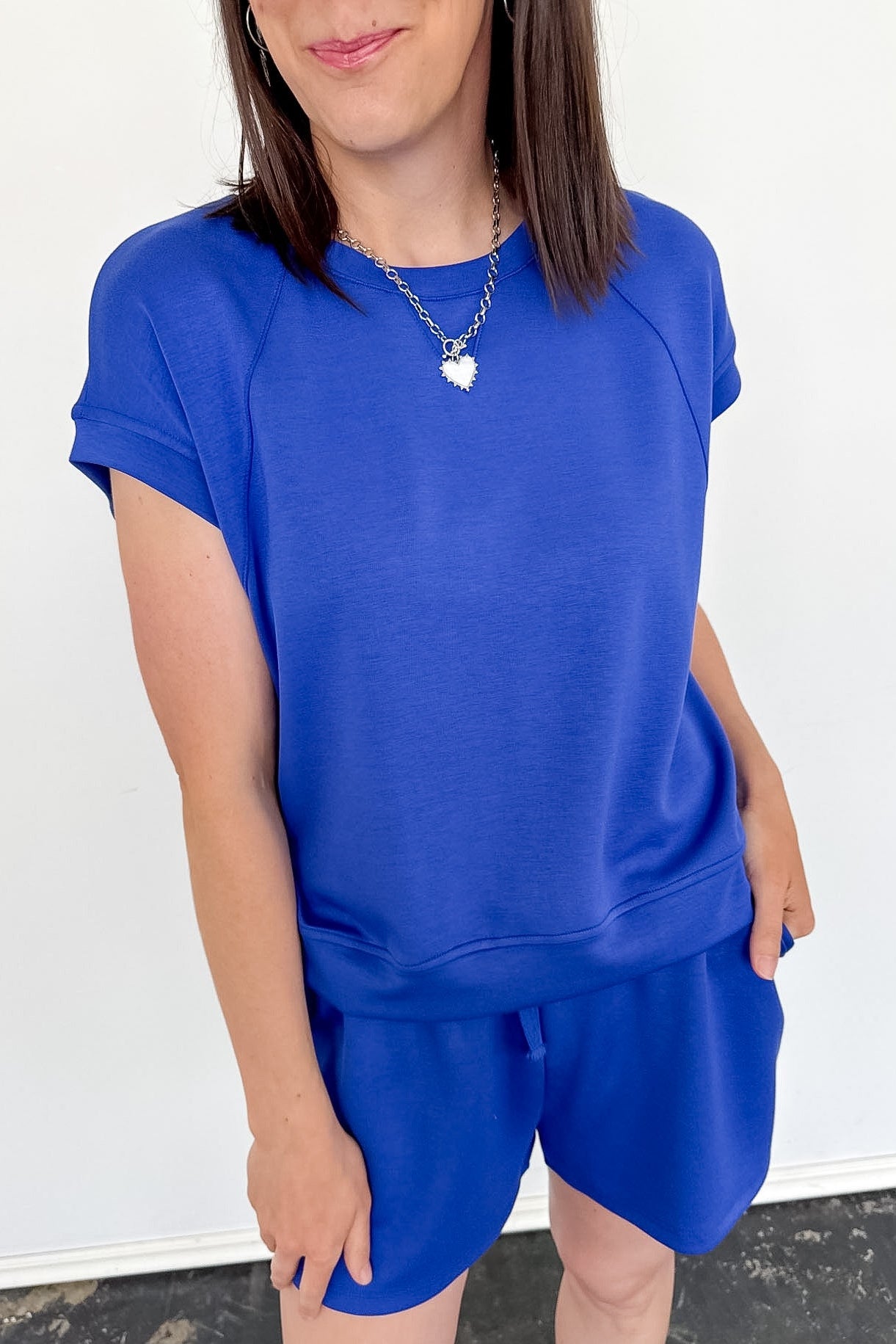 Person wearing a blue outfit with a white wall background