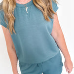 Person wearing a teal outfit with a matching top and shorts against a white background