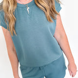 Person wearing a teal outfit with a matching top and shorts against a white background