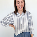 Woman wearing a striped shirt and jeans against a white background