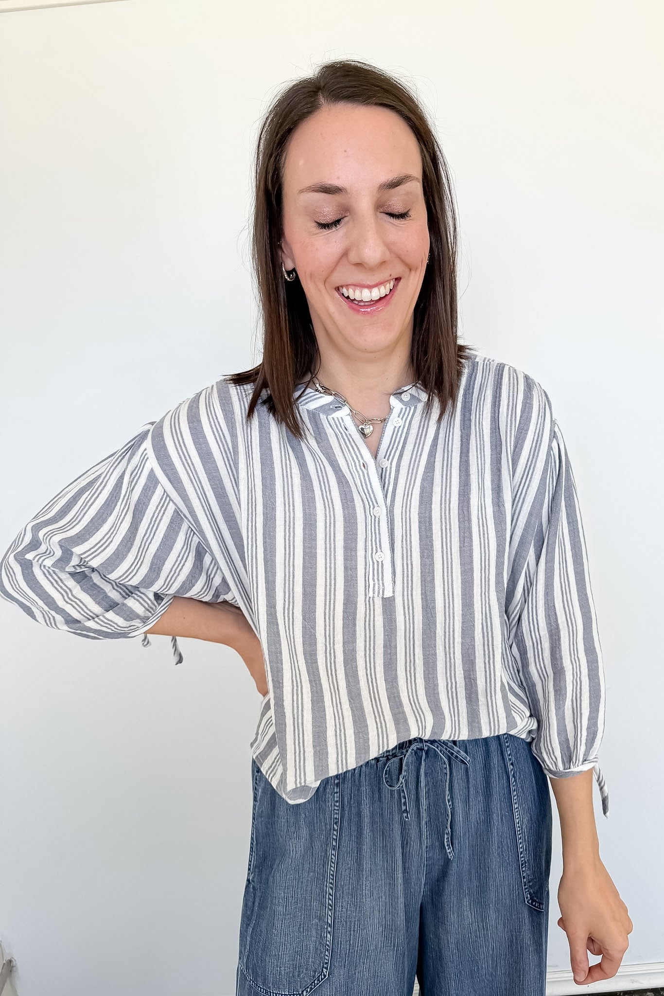 Woman wearing a striped shirt and jeans against a white background
