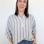Woman wearing a striped shirt and jeans against a white background