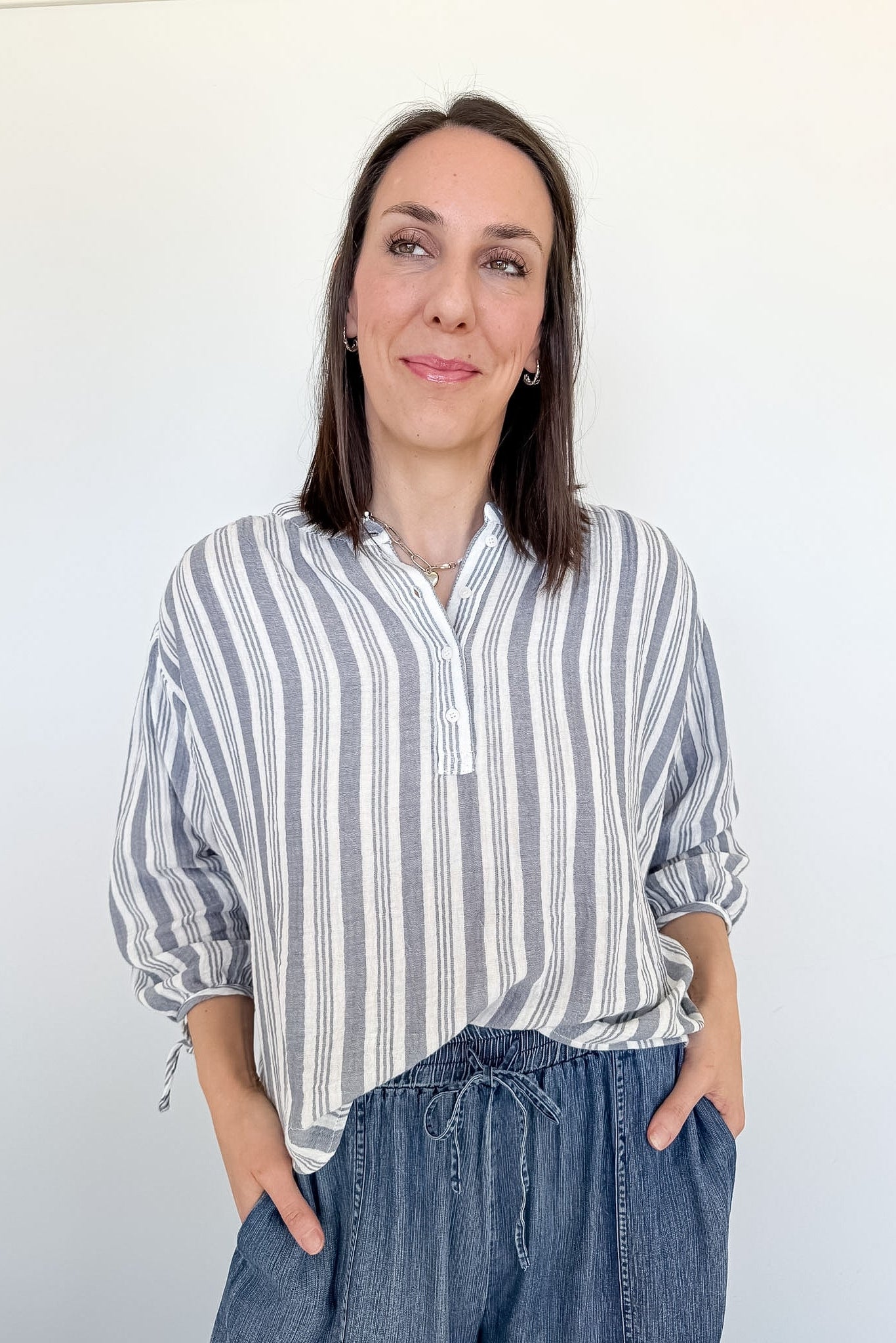 Woman wearing a striped shirt and jeans against a white background