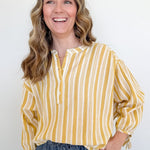 Woman wearing a yellow and white striped shirt against a plain background