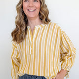 Woman wearing a yellow and white striped shirt against a plain background