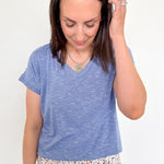 Woman wearing a blue t-shirt and floral pants against a white background