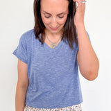 Woman wearing a blue t-shirt and floral pants against a white background